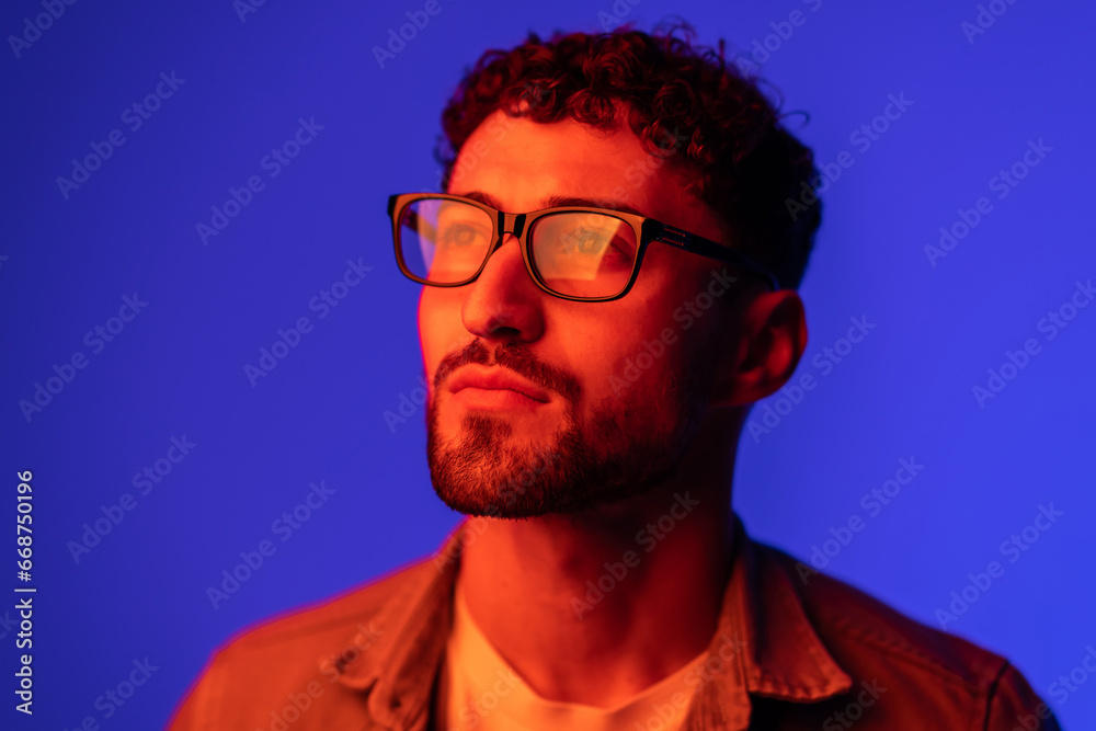 Obraz premium Portrait of young handsome man looking away against gradient purple background in neon light.