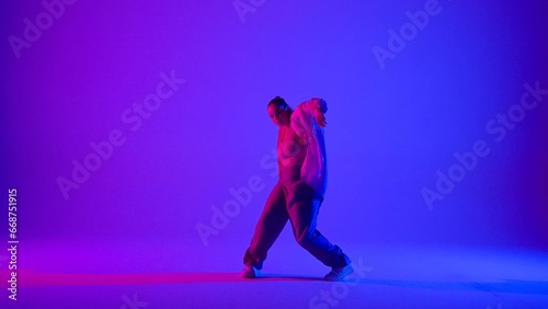 Attractive woman dancing jazz-funk on pink and blue neon background in a studio. Modern dynamic and energetic dance choreography. Full length.