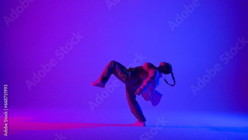 Fototapeta Naklejka Na Ścianę i Meble -  Attractive woman dancing jazz-funk on pink and blue neon background in a studio. Modern dynamic and energetic dance choreography. Full length.