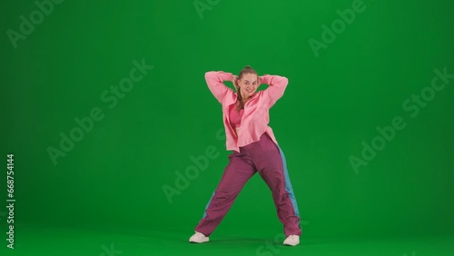Attractive woman dancing jazz-funk on green screen chroma key background in a studio. Modern dynamic and energetic dance choreography. Full length.