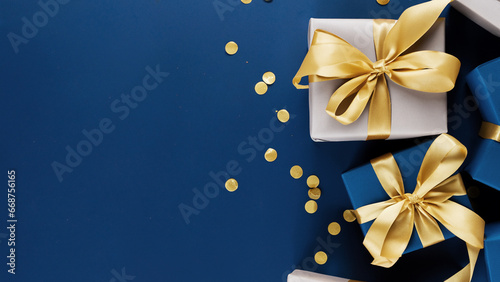 Paquets cadeaux jolis et dorés, sur un fond bleu avec des confettis. Pour anniversaire, offre spéciale, Noël photo