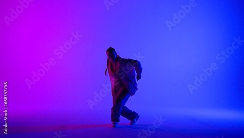 Attractive woman dancing jazz-funk on pink and blue neon background in a studio. Modern dynamic and energetic dance choreography. Full length. © kinomaster