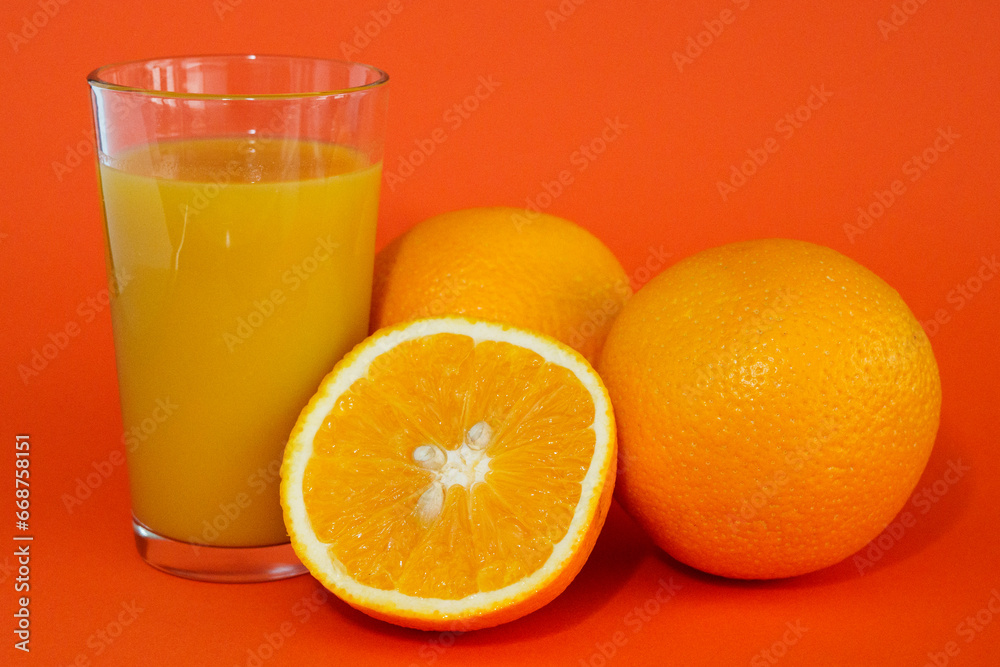 Glas of orange juice wirh oranges and cut open orange with orange background. Glas of orange juice wirh oranges and cut open orange with orange background.