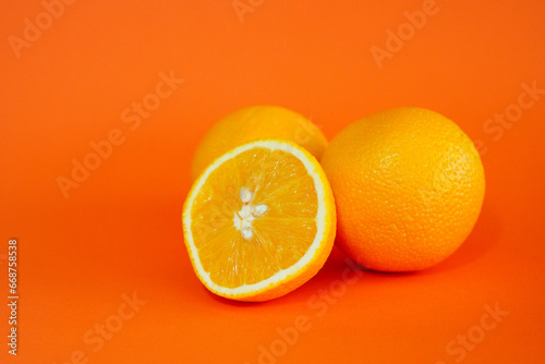 Oranges with cut open orange with orange background.