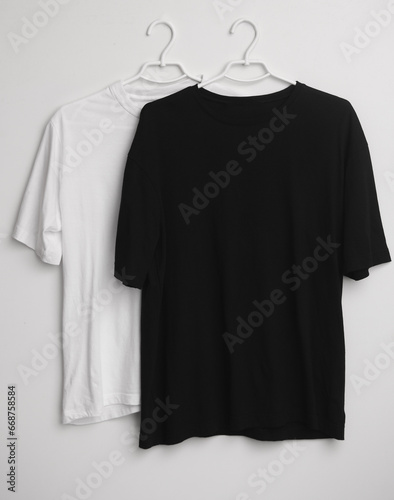 Black and white t-shirts mockup with hangers on white background