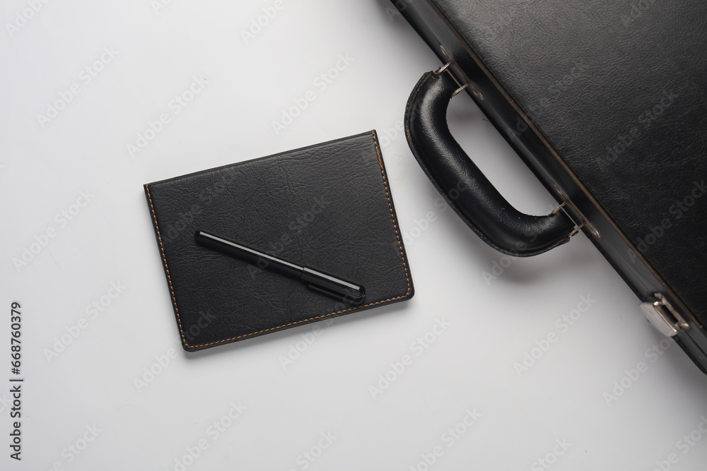 Leather suitcase with a notebook and pen on a white background. Business concept. Top view Leather suitcase with a notebook and pen on a white background. Business concept. Top view
