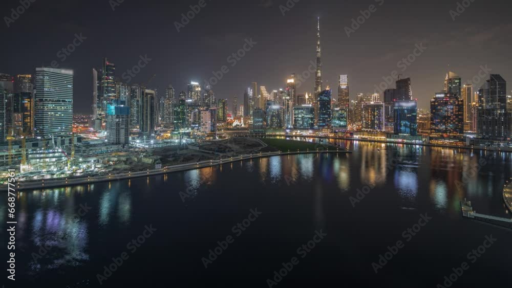 Panorama showing aerial view to Dubai Business Bay and Downtown with the various skyscrapers and towers along waterfront on canal night timelapse. Construction site with cranes Panorama showing aerial view to Dubai Business Bay and Downtown with the various skyscrapers and towers along waterfront on canal night timelapse. Construction site with cranes