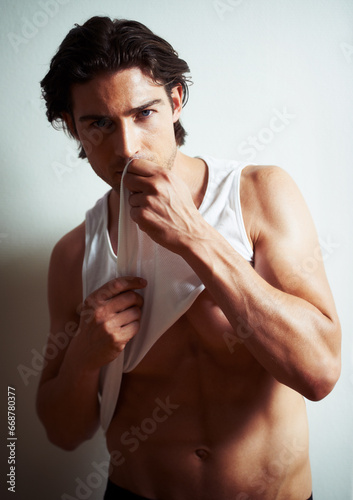 Sexy, portrait of young man in a studio with underwear for strong, body building and hot muscles. Serious, attractive and handsome male model posing in a stylish vest isolated by white background.