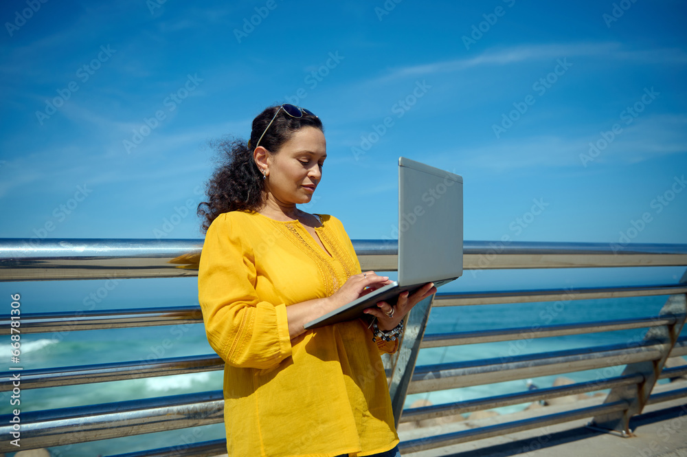 Purposeful female developer, trader, manager online working on laptop outdoor
