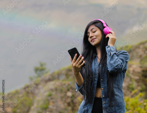 Mujer joven atractiva con auriculares disfrutando de música o un podcast en el parque o bosque, que encarna la relajación, la felicidad y la actividad de ocio. Estilo de vida saludable.