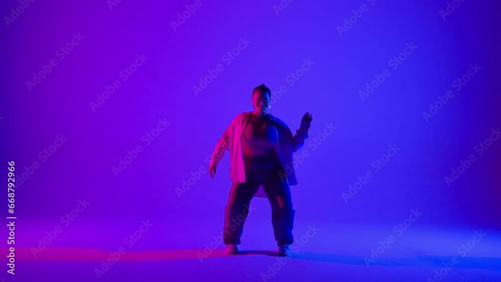Attractive woman dancing jazz-funk on pink and blue neon background in a studio. Modern dynamic and energetic dance choreography. Full length. Attractive woman dancing jazz-funk on pink and blue neon background in a studio. Modern dynamic and energetic dance choreography. Full length.