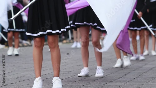 Group of cheerleaders wearing short brown skirt waving flags during a parade, close up legs