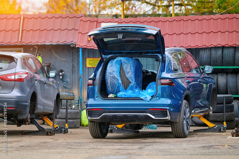 Car on hydraulic jack with removed wheels, changing tires before winter