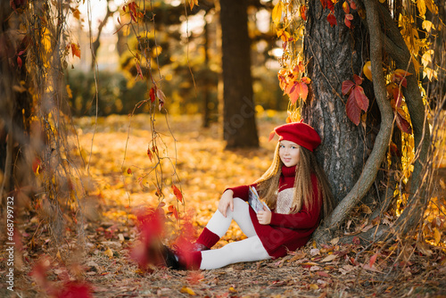 Cute baby girl with long hair in autumn in the park smiling and enjoying a sunny day and good weather sitting under a tree