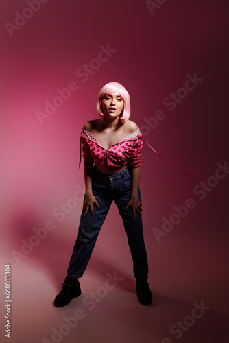 Stylish woman with pale pink hair wearing a pink jacket and jeans poses confidently against a pink background. Fashion advertising concept  individuality and confidence.