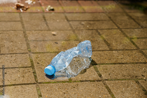 crumpled plastic bottle lies in a puddle on a street, environmental pollution photo