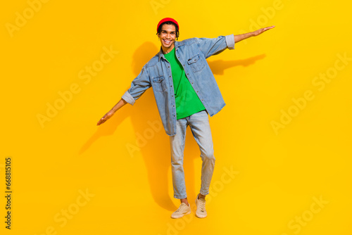Full length photo of cute young male hands wings flying plane wear trendy jeans garment isolated on yellow color background