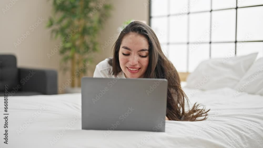 Young beautiful hispanic woman using laptop lying on bed at bedroom Young beautiful hispanic woman using laptop lying on bed at bedroom