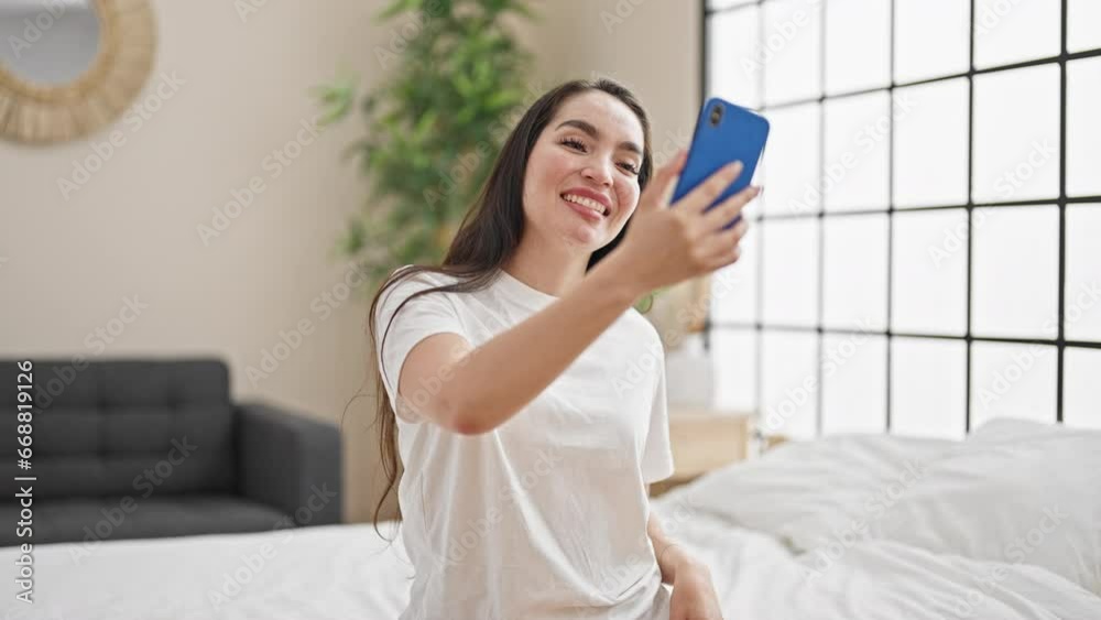 Young beautiful hispanic woman doing video call sitting on the bed at bedroom Young beautiful hispanic woman doing video call sitting on the bed at bedroom