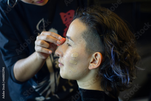 young woman being made up by a professional makeup artist in a dressing room