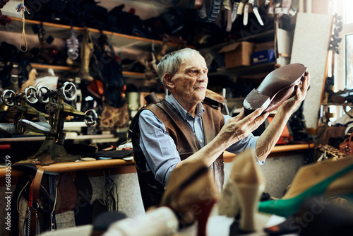 Elderly shoemaker working in a shop