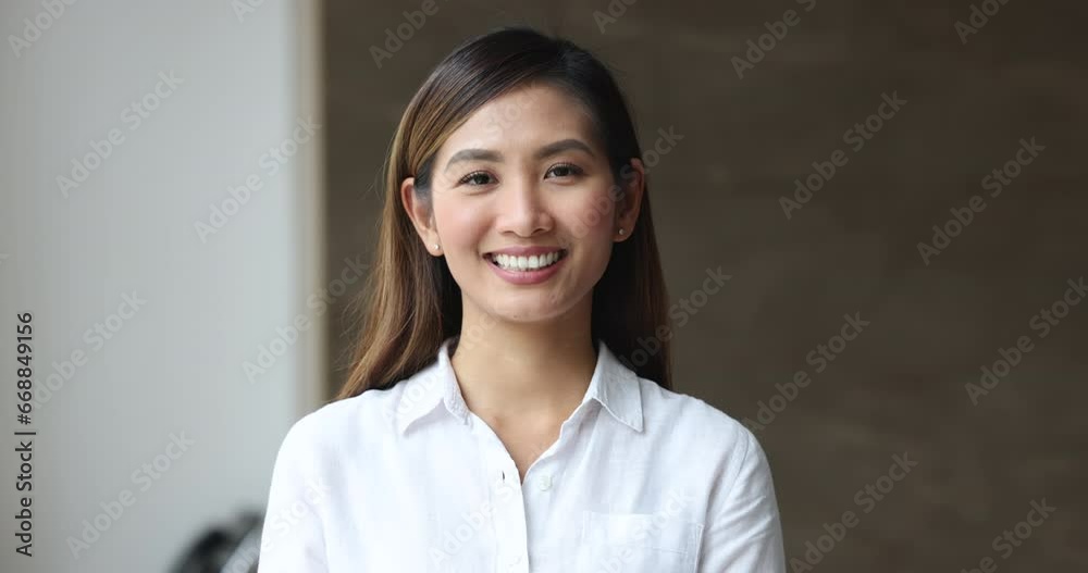 Attractive young Malaysian businesswoman pose in office, smile, look at camera standing alone at modern workplace. Hiring, company CEO or applicant, successful professional employee head shot portrait Attractive young Malaysian businesswoman pose in office, smile, look at camera standing alone at modern workplace. Hiring, company CEO or applicant, successful professional employee head shot portrait