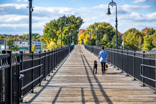 Girl in sportswear walking her dogs on a leash walks along a footbridge in Manchester