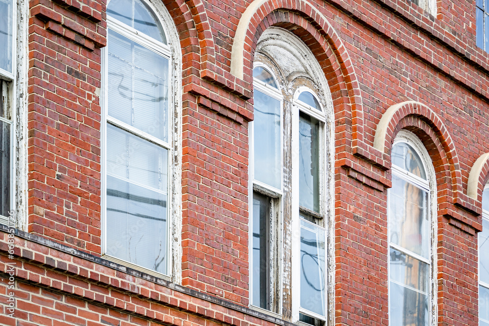 Old arched windows in a multi-story brick building with relief masonry of cornices and arches