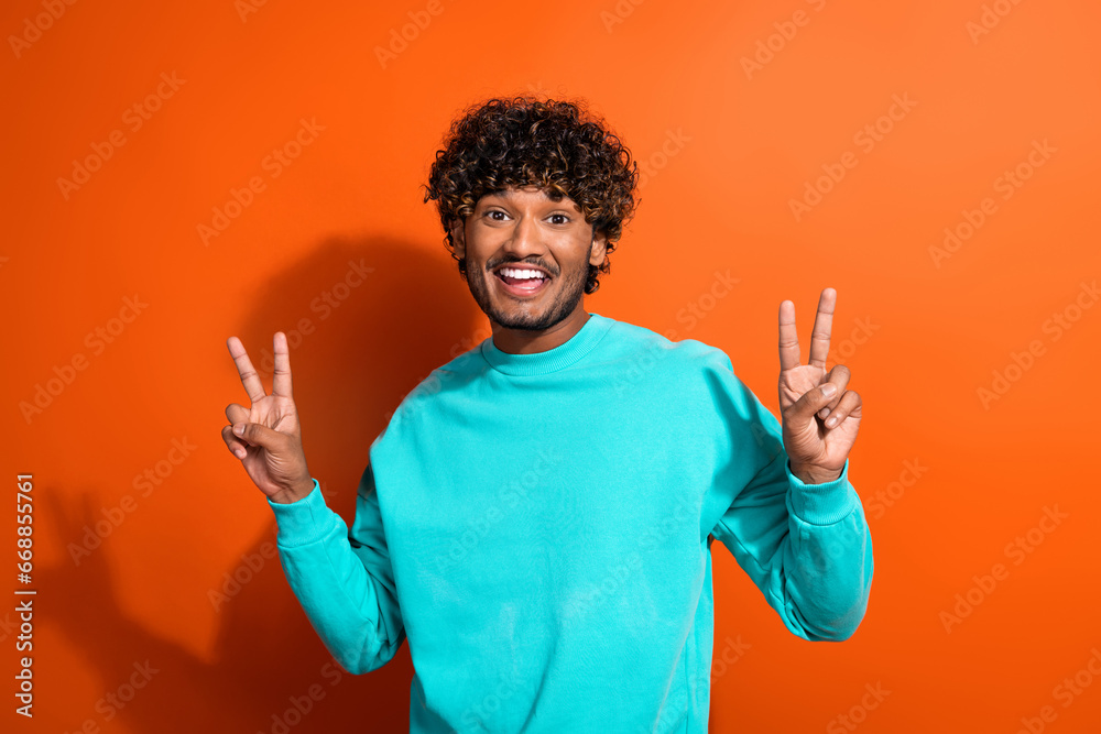Photo of positive nice person toothy smile hands fingers demonstrate v-sign isolated on orange color background Photo of positive nice person toothy smile hands fingers demonstrate v-sign isolated on orange color background