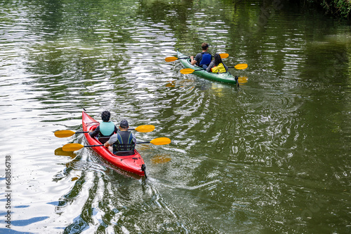 Two couples of men and women are kayaking on the quiet lake Lacamas