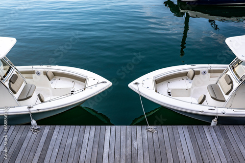 Two identical motor boats are moored at a wooden pier in Boston Bay on the Atlantic coast