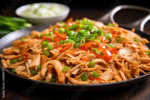 close up of pulled chicken garnished with chopped green onions