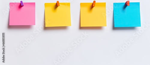 A blue magnet holds the post it paper on a white background with space for writing surrounded by a colorful pinboard photo
