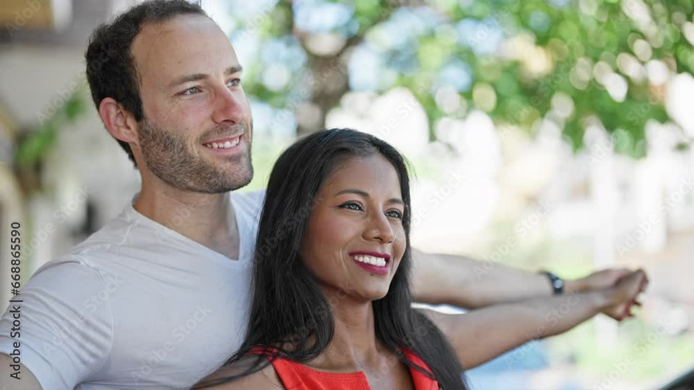 Beautiful couple standing together with arms open smiling at street