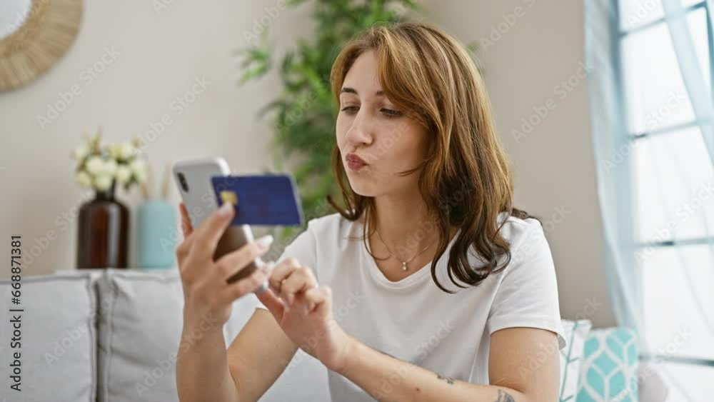 Young woman shopping with smartphone and credit card sitting on sofa at home Young woman shopping with smartphone and credit card sitting on sofa at home