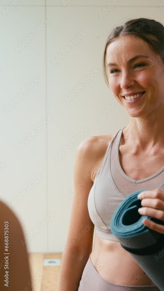 Vertical video of two female friends talking and catching up at gym or yoga studio for exercise - shot in slow motion Vertical video of two female friends talking and catching up at gym or yoga studio for exercise - shot in slow motion