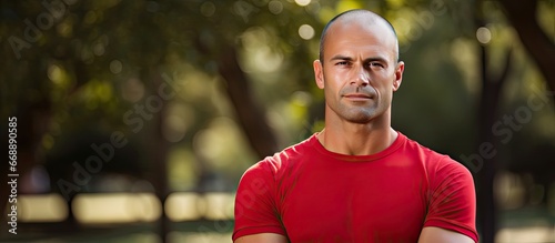 Man wearing red shirt standing outdoors in park photo