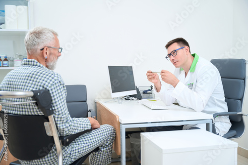 Therapist communicates with a gray-haired man in a doctors office