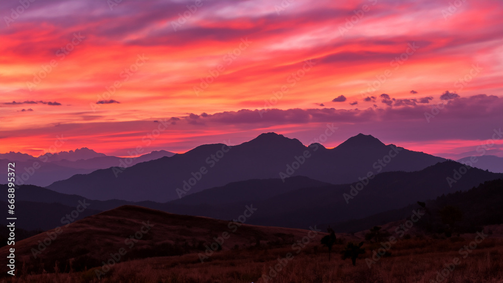 Sonnenuntergang in den Bergen: Rote, rosa und orange Himmel über lila Gipfeln