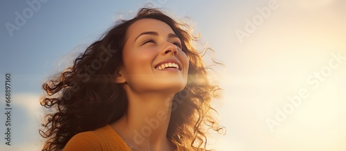 Joyful Brazilian woman praising God while gazing at the sky with a smile © AkuAku