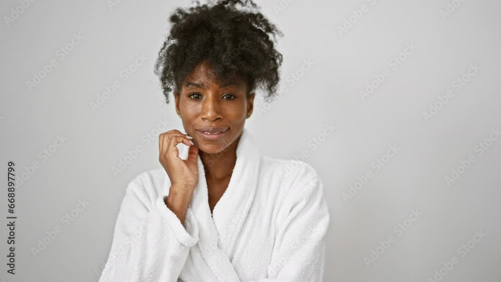 African american woman wearing bathrobe touching face over isolated white background African american woman wearing bathrobe touching face over isolated white background