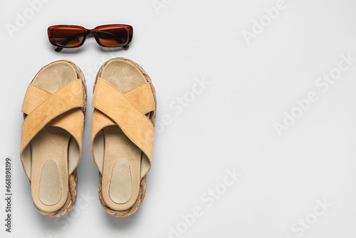 Stylish beige sandals and sunglasses on grey background
