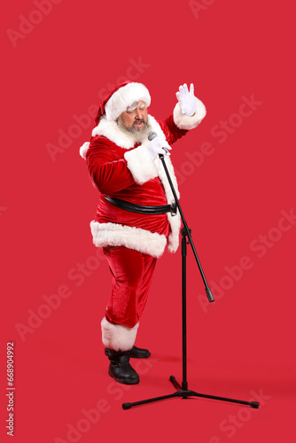 Cool Santa Claus with microphone singing Christmas song on red background