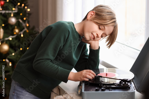 Cute little boy listening music through record player at home  on Christmas eve