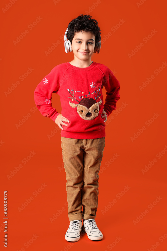 Fototapeta premium Cute little boy in headphones orange background