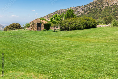 Casa rústica de piedra en un prado verde cerca de la montaña photo
