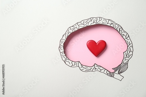 Emotional thinking. Red heart on pink background, top view through paper with brain shaped hole and drawing. Space for text photo