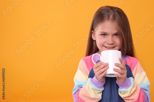 Happy girl with white ceramic mug on orange background  space for text