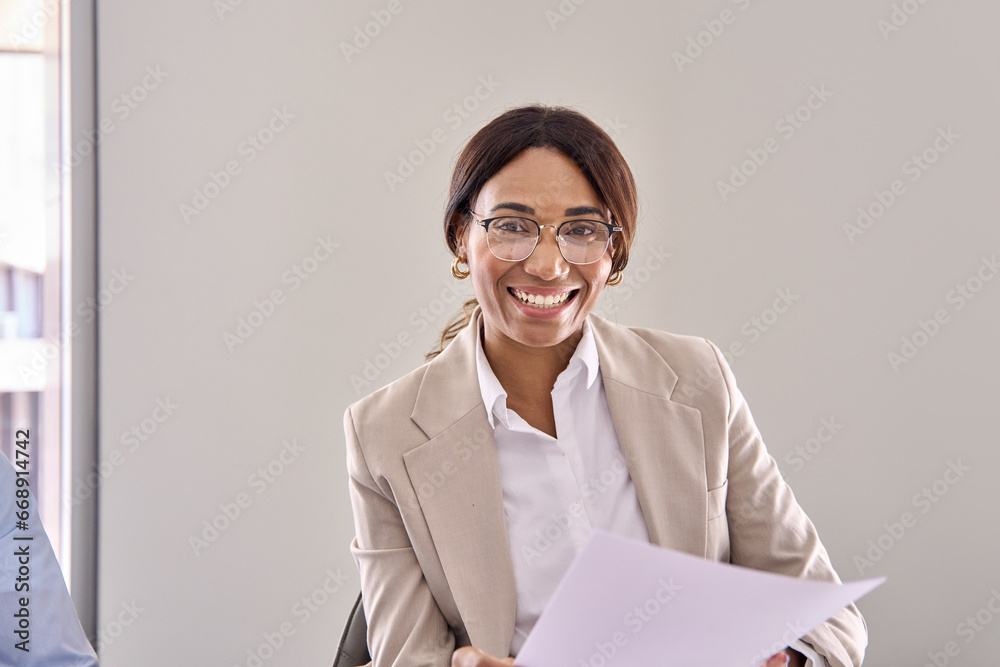 Smiling African American business woman hr manager, lawyer or attorney wearing suit holding documents consulting bank client during legal advice, communicating with recruit at interview meeting. Smiling African American business woman hr manager, lawyer or attorney wearing suit holding documents consulting bank client during legal advice, communicating with recruit at interview meeting.