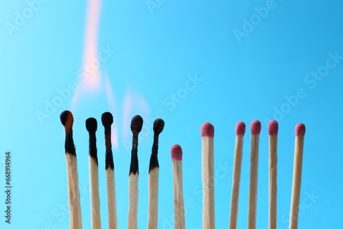 Burning and whole matches on light blue background. Space for text